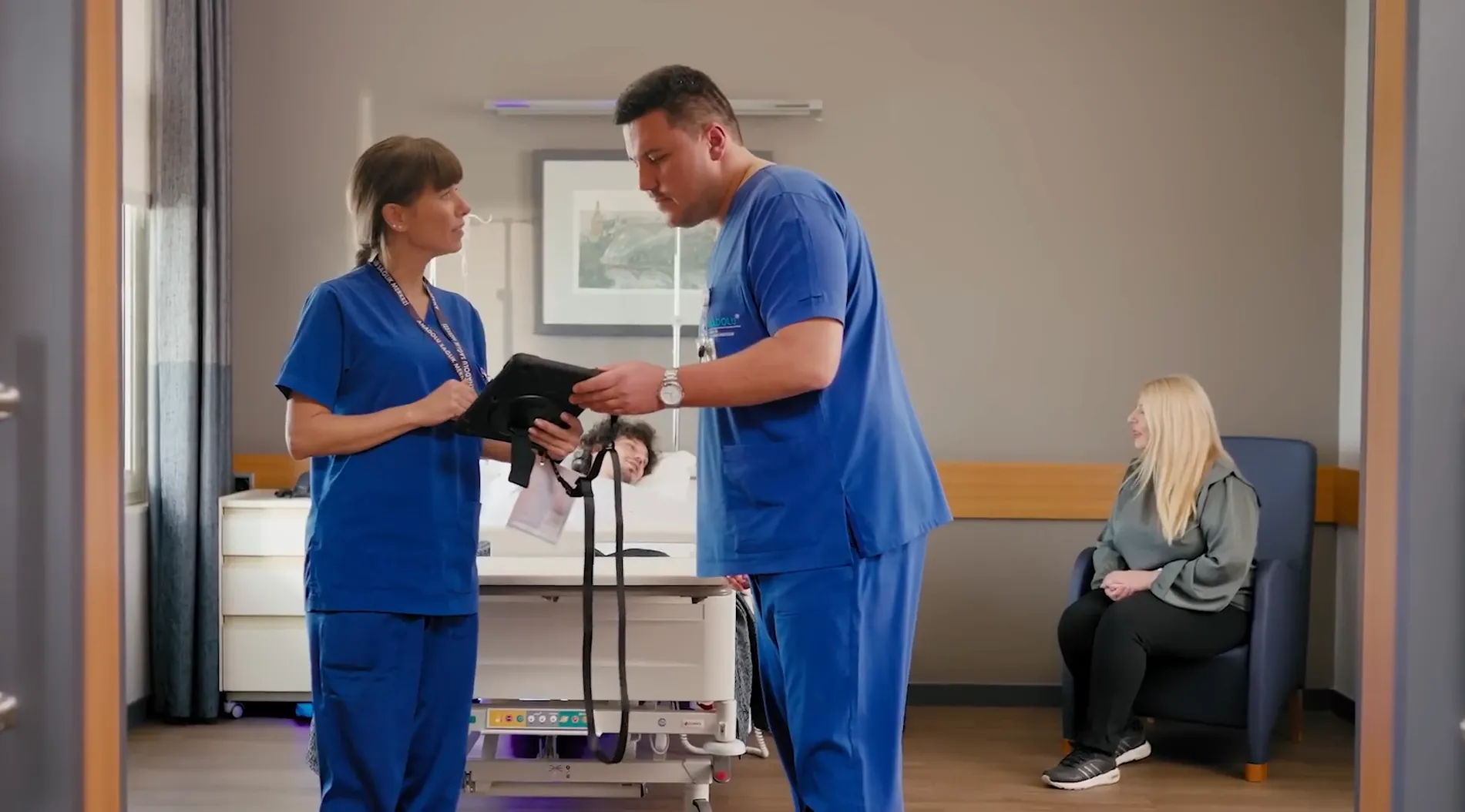 Nurse assisting a smiling patient sitting in a wheelchair in a hospital corridor